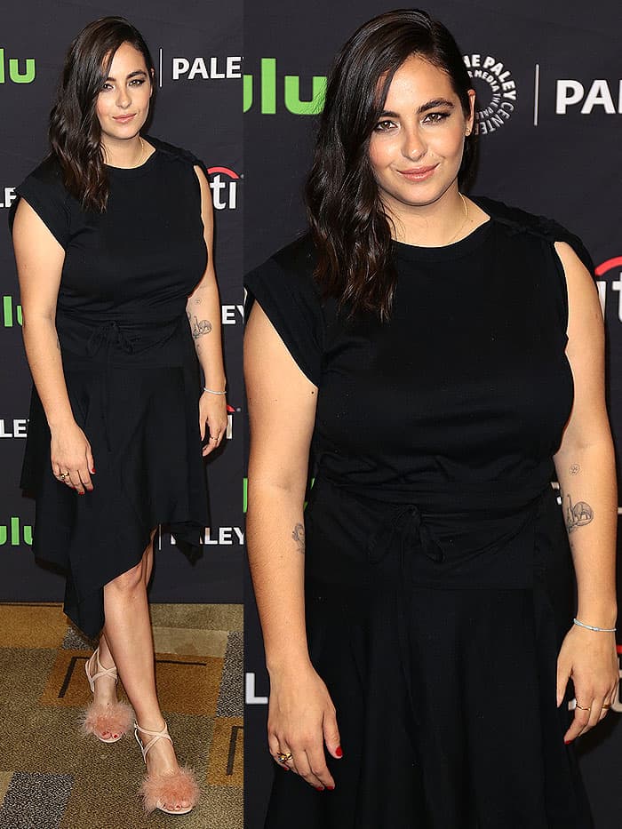 Alanna Masterson keeps it chic yet playful in a black tie-waist dress with a handkerchief hem, letting her fluffy pink feather-topped sandals steal the spotlight