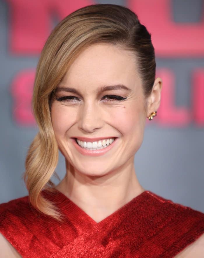 Brie completes the look with soft, side-swept waves and subtle makeup that balances the intensity of her vibrant red dress