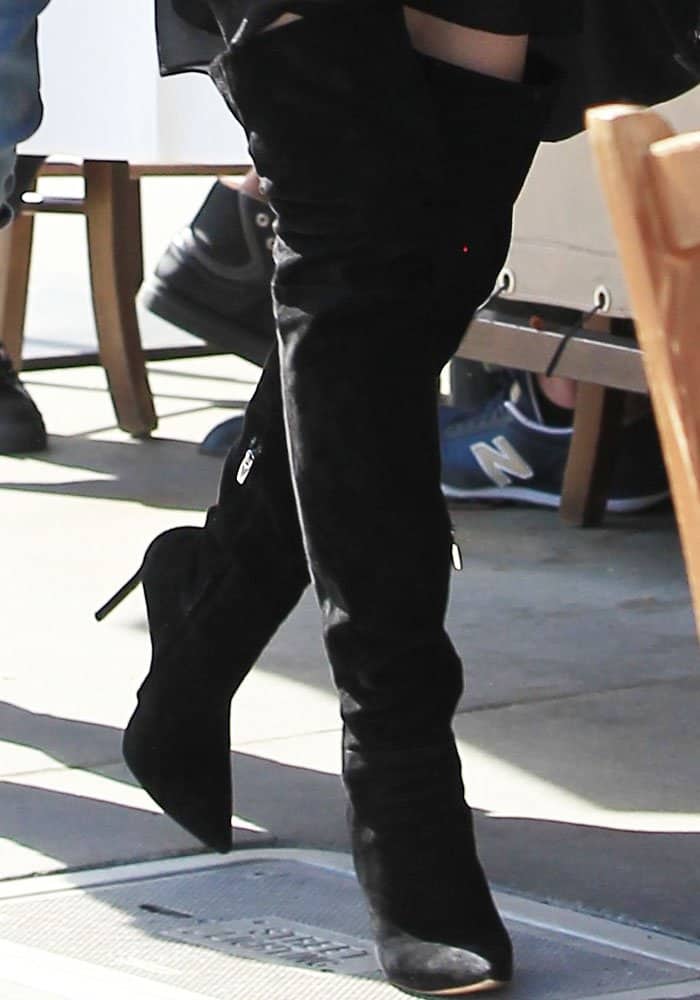 Chrissy Teigen steps out in effortlessly chic Gianvito Rossi "Dree" thigh-high boots, elevating her all-black ensemble with sleek, statement-making style