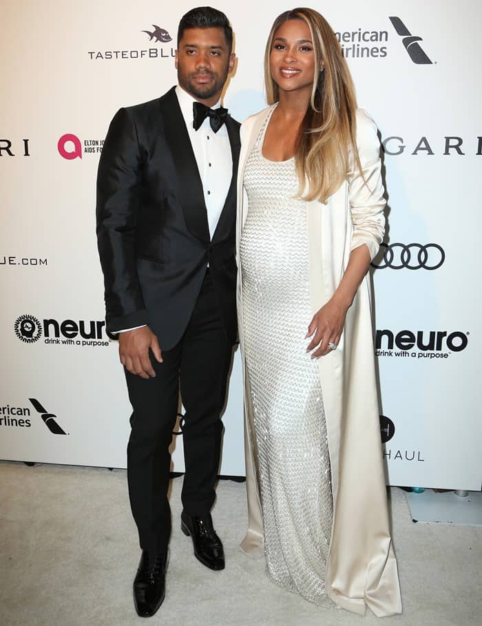 Ciara glows in a silky August Getty gown paired with Giuseppe Zanotti sandals, while Russell Wilson stuns in a classic tux at Elton John’s Oscars Party