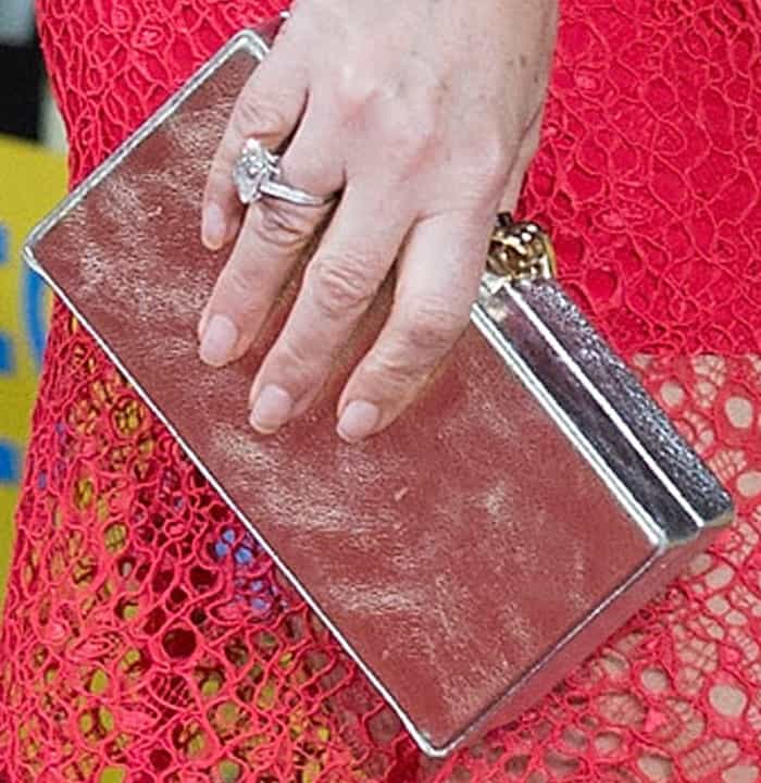 Elizabeth Hurley perfectly contrasts her vibrant red lace dress with a sleek silver clutch and a dazzling statement ring