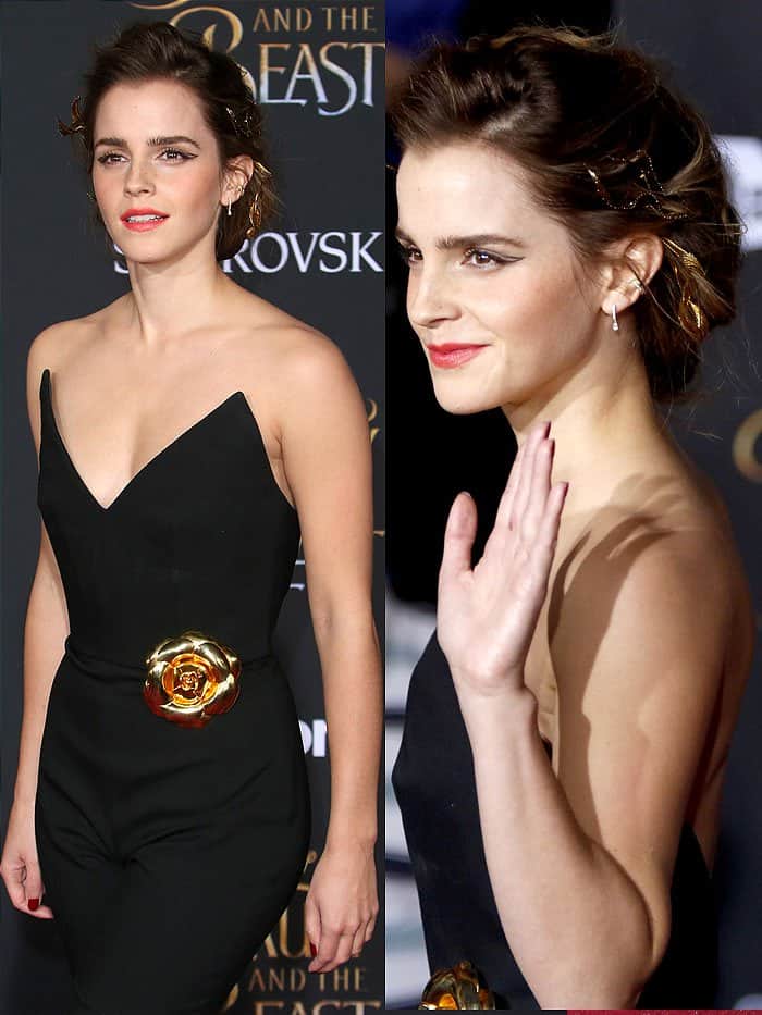 Emma Watson styles her look with subtle sophistication, showcasing a deep V-neckline on her Oscar de la Renta jumpsuit, drawing attention to a graceful, minimalist display of cleavage balanced with an elegant gold flower brooch