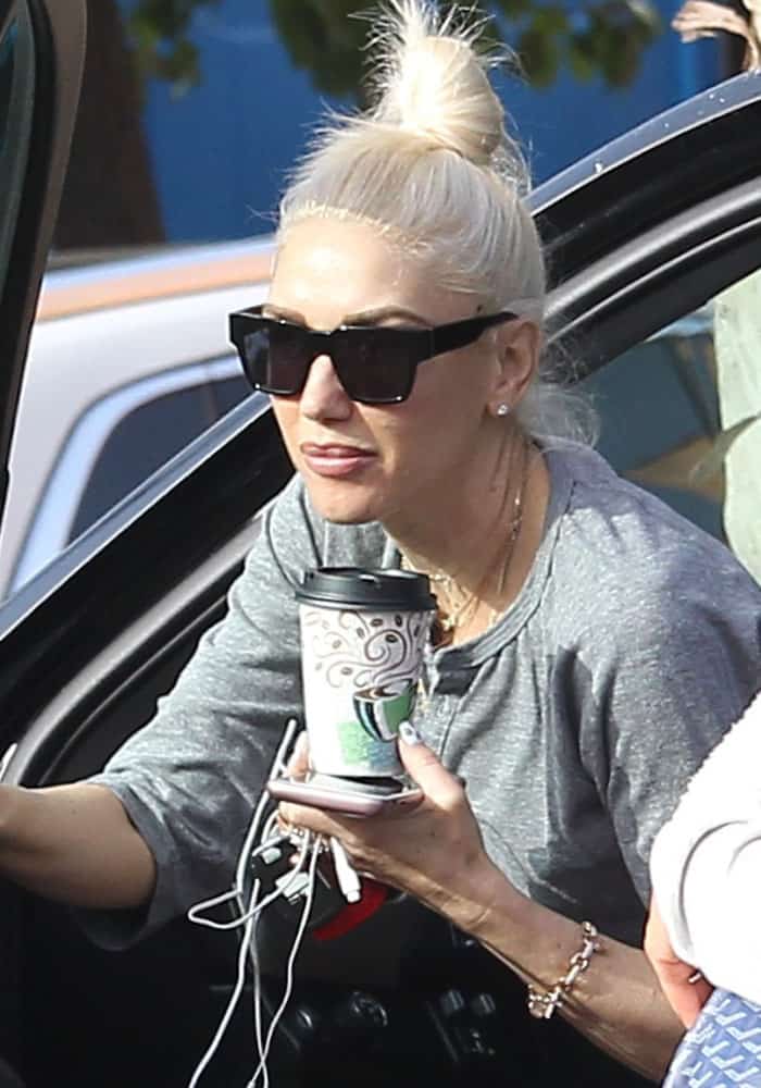 Gwen Stefani keeps her look understated with a gray top, oversized sunglasses, and a casual topknot