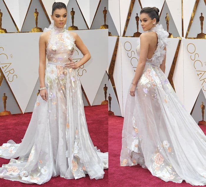 Hailee Steinfeld captivates in a whimsical Ralph Russo gown featuring floral appliqués, sheer panels, and a dramatic flowing train that exudes ethereal charm