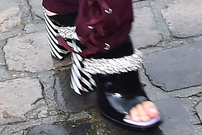 Black leather mules with black-and-white-striped chunky heels and embellished metal chain vamp straps on Hailey Baldwin