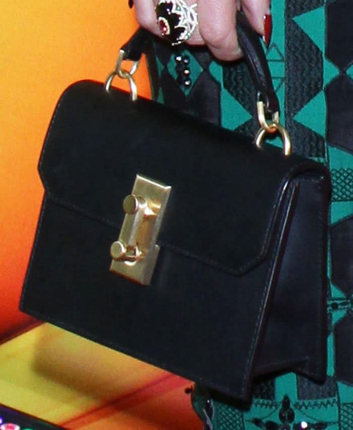 Accessorizing her unique look, Jennifer Beals complements her outfit with a sleek black structured bag, adding a sophisticated finish