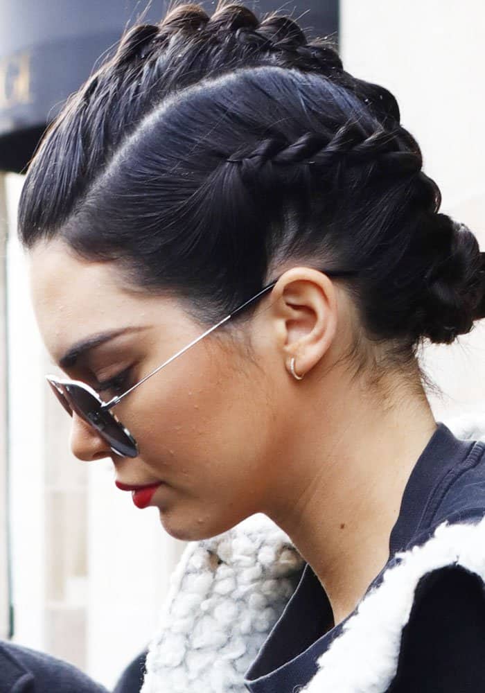 Kendall Jenner keeps her Paris look sleek with braided hair, aviator shades, and a bold red lip that adds instant polish