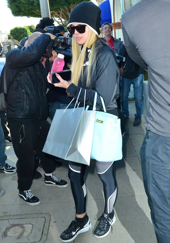 Juggling shopping bags and a baby blue Hermès Birkin, Khloé steps out in a sleek Nike athleisure look that blends function with understated luxury