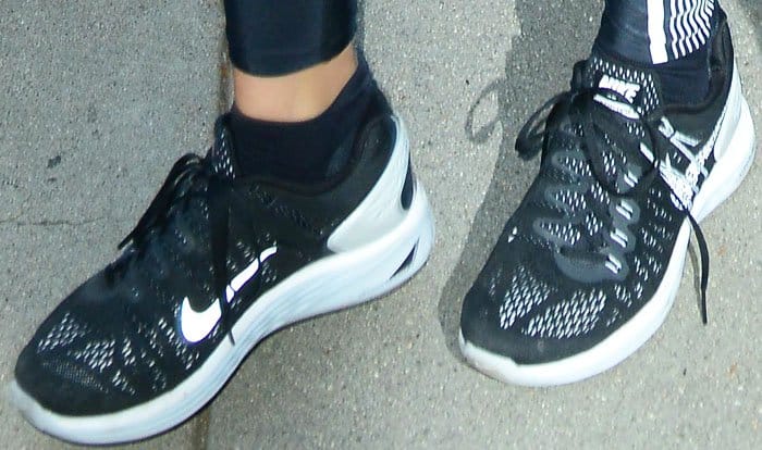 A close-up reveals Khloé’s black Nike LunarGlide 7 sneakers, their lightweight mesh and white sole emphasizing comfort-driven design