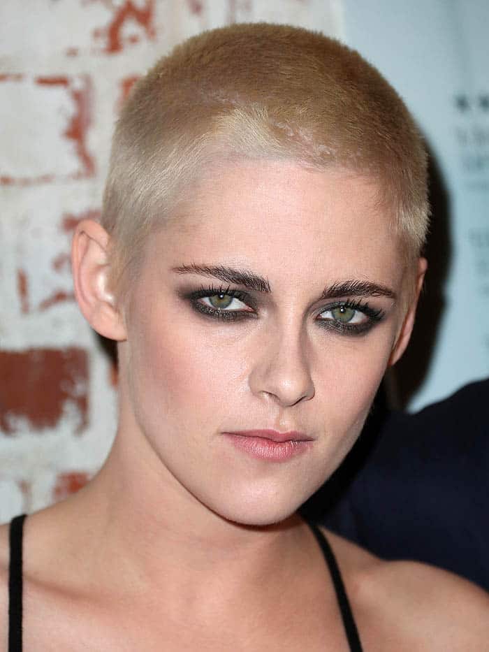 Kristen Stewart debuts her bold blonde buzz cut, showcasing fierce, smoky eye makeup that highlights her green eyes and enhances her confident and rebellious look