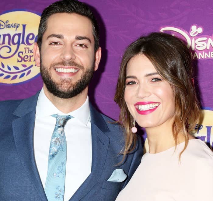 Mandy Moore reunites with her 'Tangled' co-star Zachary Levi, both beaming with red carpet charm—her soft waves and pink-hued glam perfectly complementing his dapper blue suit and floral tie