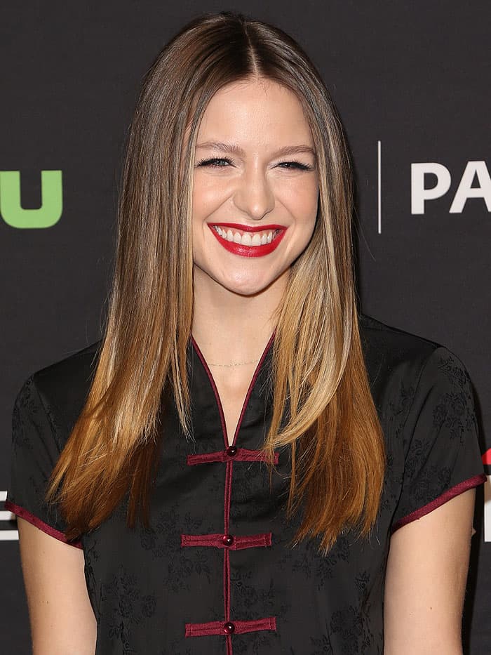 Melissa Benoist's hairstyle features sleek, straight locks with a center part, creating a polished and modern look