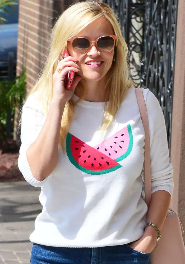 Reese Witherspoon chats on the phone while rocking a playful watermelon-print sweater during a sunny stroll in Santa Monica on March 10, 2017