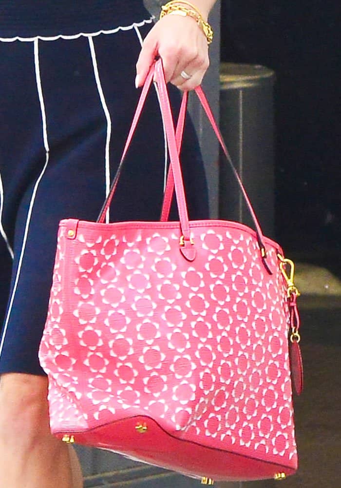 Reese Witherspoon accessorizes her look with a bold pink Draper James printed tote and gold jewelry
