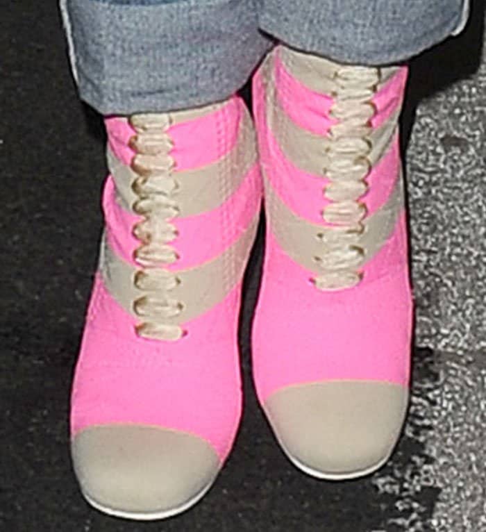 A close-up reveals the vibrant neon-pink fabric, sporty beige stripes, and unique lacing of Rita Ora's Fendi sock boots