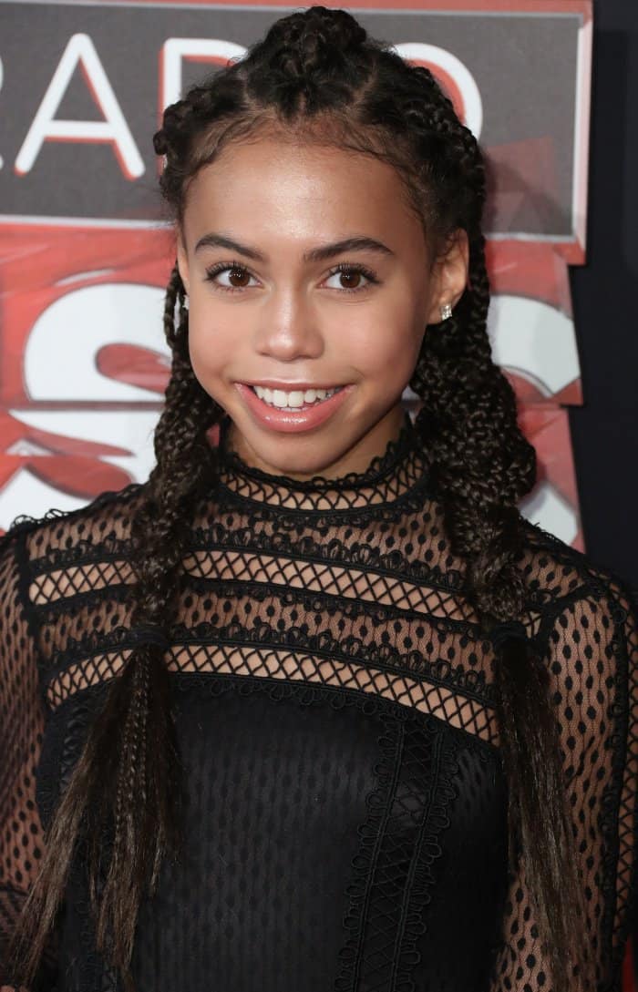 Her polished beauty look and braided hairstyle contrast with the sharp simplicity of her strappy heels, keeping the focus on streamlined styling