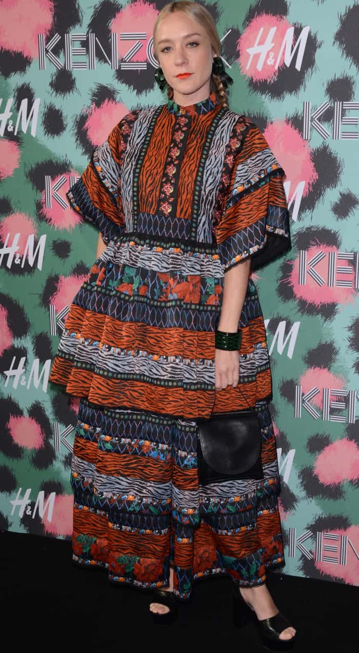 Chloë Sevigny brings her signature edgy elegance to the Kenzo x HM fashion show, styling the bold patterned maxi dress with sleek braids, statement accessories, and black platform heels