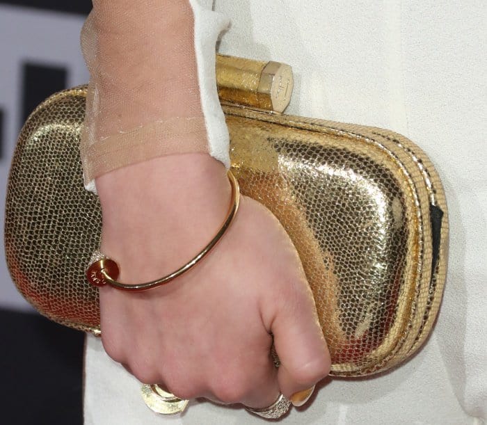 A gold minaudière with a textured finish brings vintage polish, catching the light with every movement of her hand