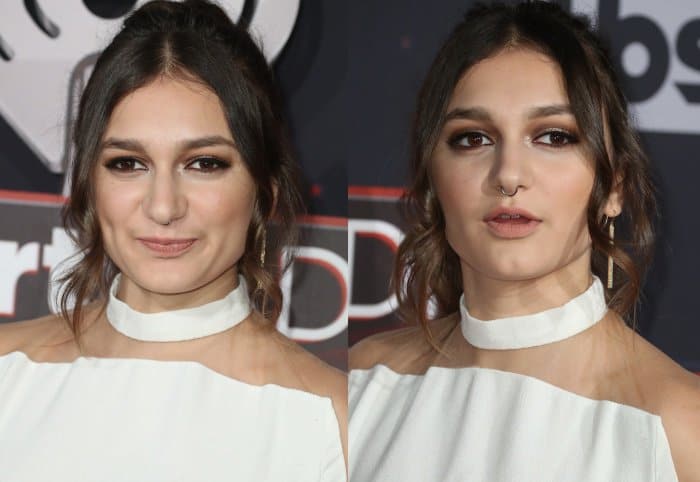 A soft, face-framing updo and warm smoky eyes balance the architectural neckline, keeping the look refined despite its daring cutouts