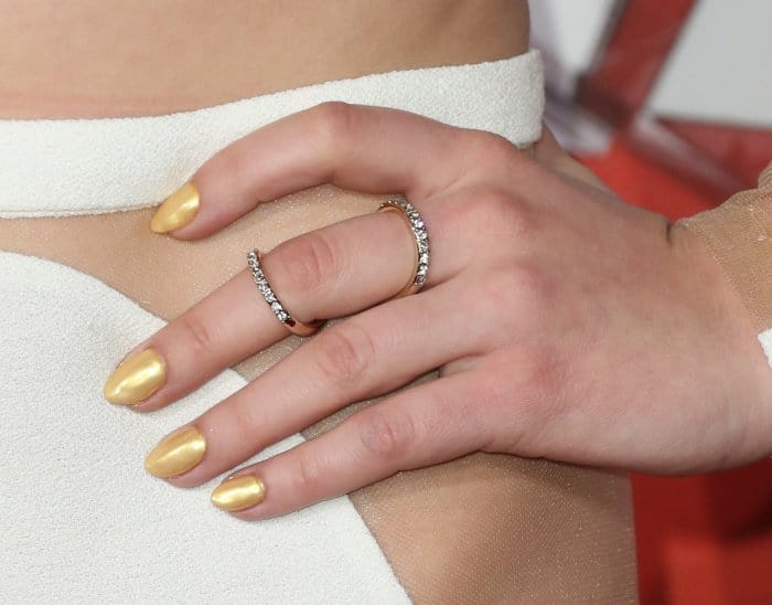 Stacked diamond bands and molten gold nails add a subtle flash of texture, echoing the metallic accents woven throughout the look