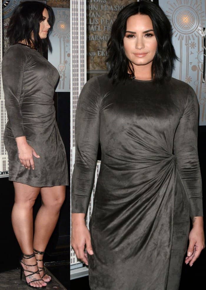 Demi Lovato paired tousled waves and glossy nude lips with a draped Josie Natori dress and Stuart Weitzman “XChain” sandals