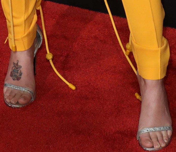 A detailed look at her feet shows the barely-there toe strap of the Nudistsong sandals, their slim metallic band catching the light against the red carpet
