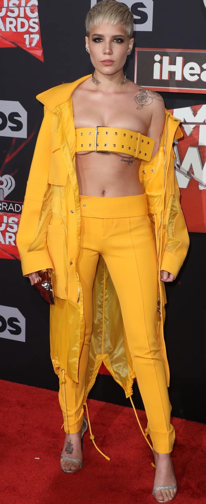 Halsey commands attention in a saturated yellow Versus Versace ensemble, anchoring the look with a bold belt-turned-bandeau and a sleek silver choker that sharpens the industrial edge