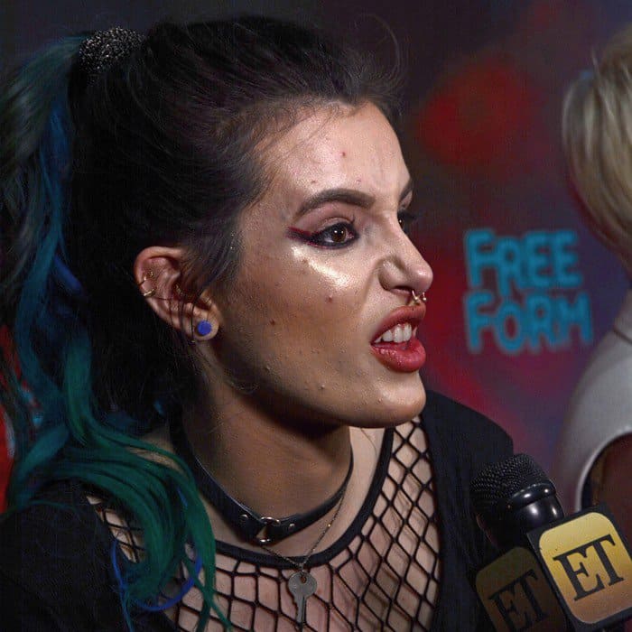 A close-up of Bella Thorne at the Freeform UpFronts, showing her distinctive makeup, faux leather charm choker, and fishnet top detail