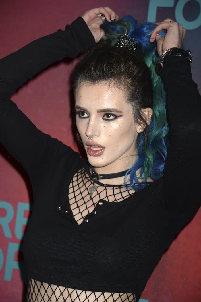 Bella Thorne adjusts her turquoise-streaked ponytail while at the Freeform UpFronts, showing off her bold winged eyeliner and a faux leather choker with a key charm
