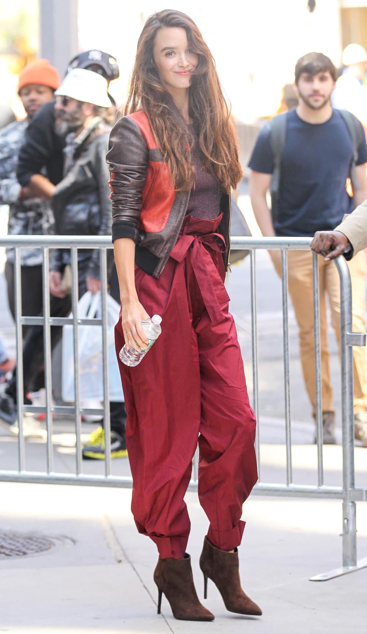Charlotte Le Bon arrived at the Build Series in New York on April 18, 2017, wearing a Sophie Theallet Spring 2017 color-block raffia bomber jacket, a Paule Ka Resort 2017 purple lurex crewneck knit sweater, cranberry red high-waisted paper bag trousers, complemented by Stella Luna 'Indispensable' brown suede booties, and side-parted tresses