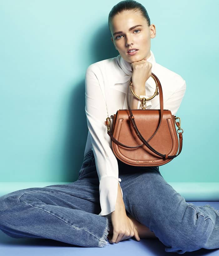 Effortlessly chic in a crisp white blouse and wide-leg denim, the model showcases the Chloé Nile bag in rich tan leather with its iconic bracelet handle