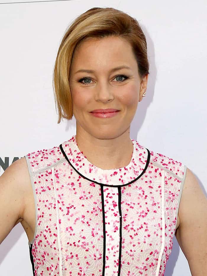 Elizabeth Banks pairs her racing-inspired Fendi dress with a soft, rosy makeup palette and a modern sideswept hairstyle to balance the bold graphic lines of her outfit