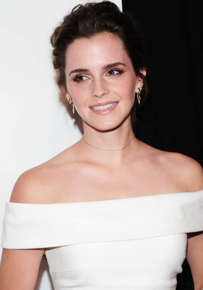 Emma’s soft updo and subtle jewelry keep the focus on her statement neckline