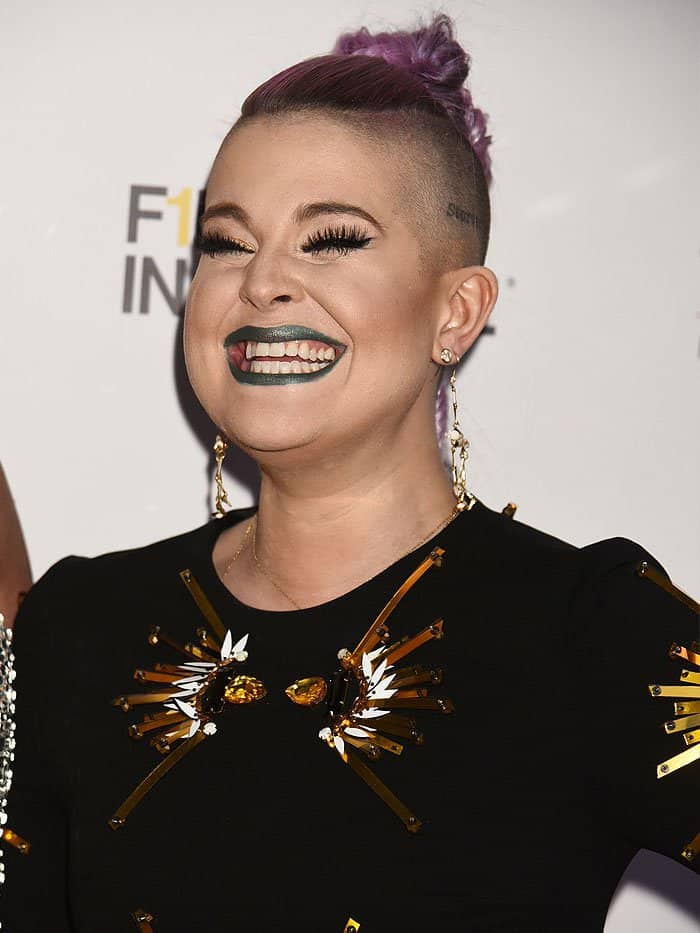 Kelly Osbourne radiating joy as she showcases her bold purple braided mohawk and metallic green lipstick at the Bella Magazine cover launch party in NYC