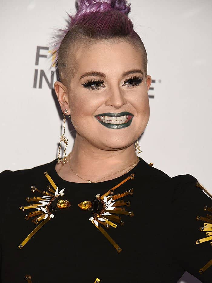 Kelly Osbourne flaunting her unique style with a braided mohawk and metallic green lipstick