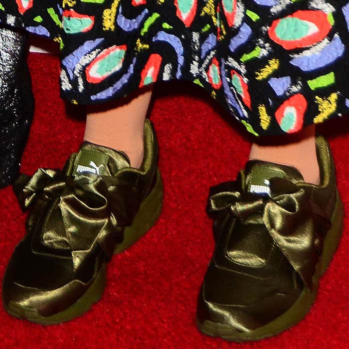 Close-up of the olive green Fenty Puma by Rihanna bow sneakers on Lena Dunham