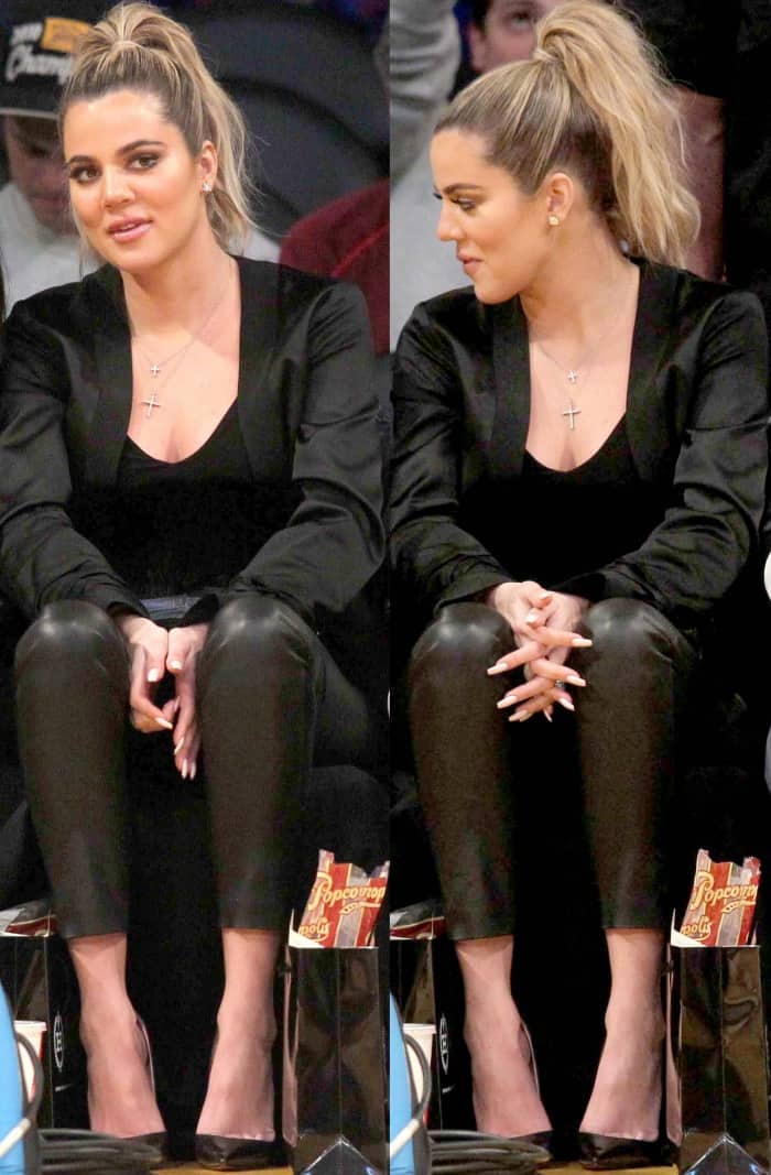 Khloé Kardashian wearing a black jacket, a black low-cut top, black leather leggings, and black pointy-toe pumps at the Lakers vs. Cavaliers basketball game
