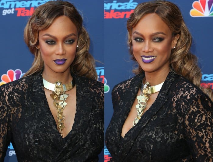 Tyra Banks shows off her sculpted waves, metallic statement necklace, and bold purple lipstick that add dramatic contrast to her black lace suit