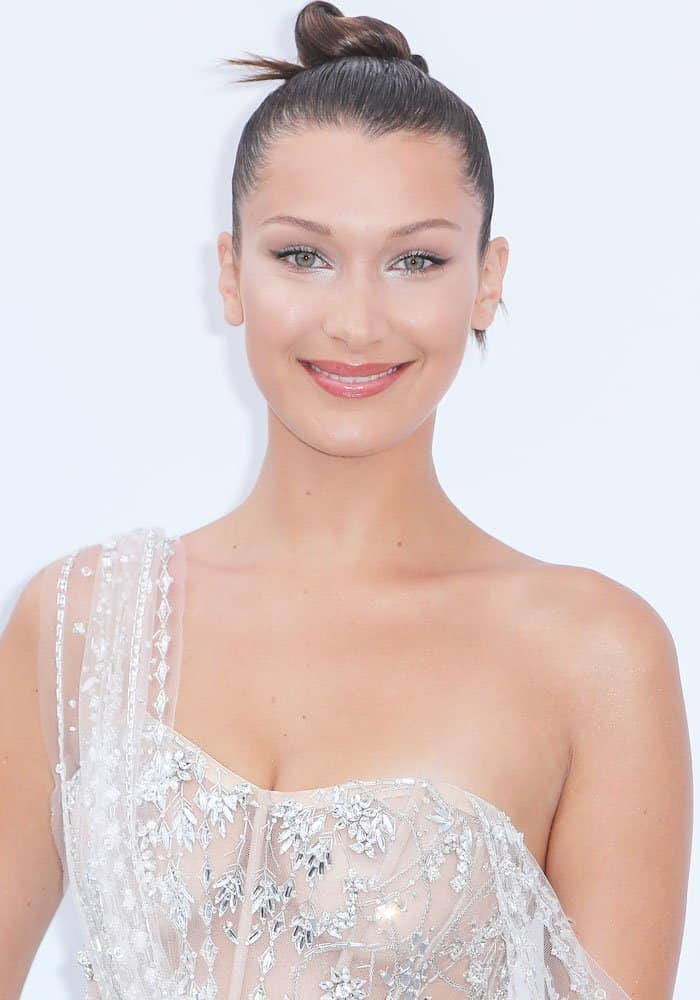 Bella Hadid stuns with a sleek, high-knotted bun, perfectly complementing her ethereal sheer gown and minimal diamond-studded jewelry