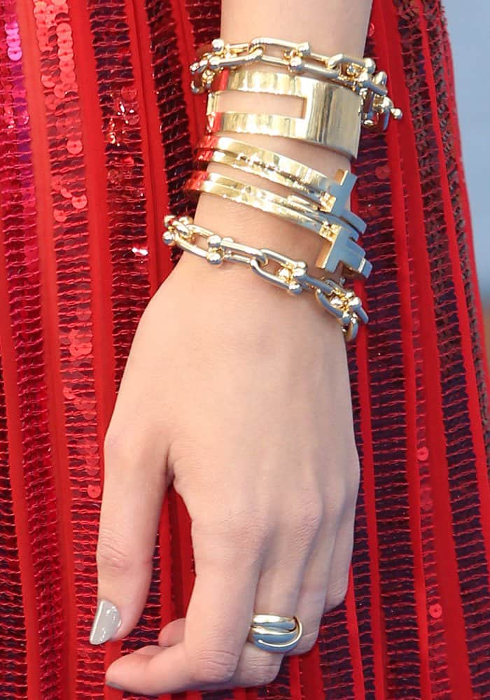 Gal Gadot completes her look with stacked gold Tiffany Co. bracelets, a sculptural ring, and a glossy neutral manicure that adds subtle elegance