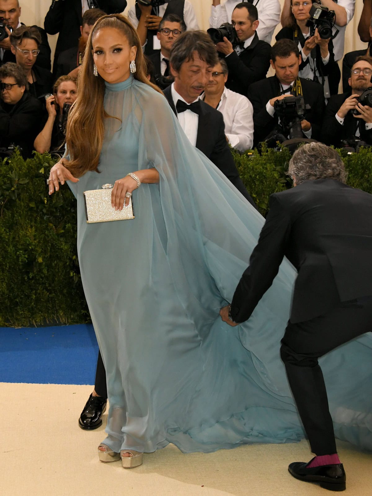 An attendant briefly lifted the flowing Valentino train, revealing Jennifer Lopez's metallic Giuseppe Zanotti Amelia platform sandals beneath the pale blue couture gown at the 2017 Met Gala
