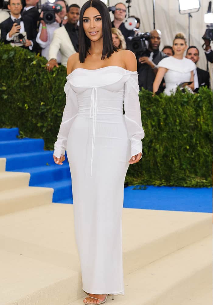 Kim Kardashian showcases understated elegance at the 2017 Met Gala in a white off-the-shoulder Vivienne Westwood gown, paired with barely-there Yeezy sandals that elongated her frame