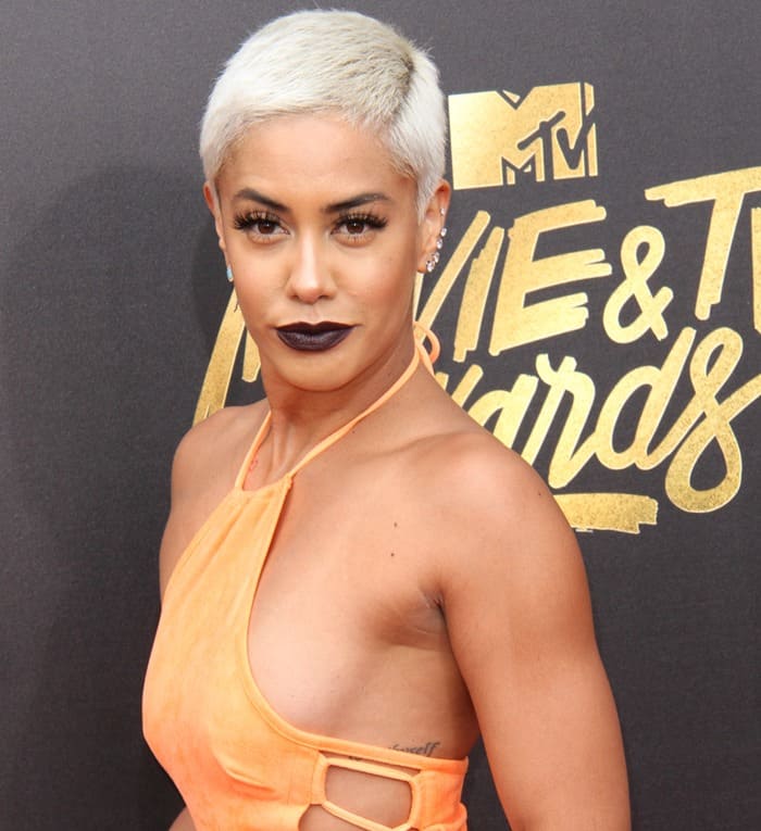 Sibley Scoles confidently posed in a daring side-boob revealing orange dress, showing off her small heart tattoo under her arm at the MTV Movie  TV Awards