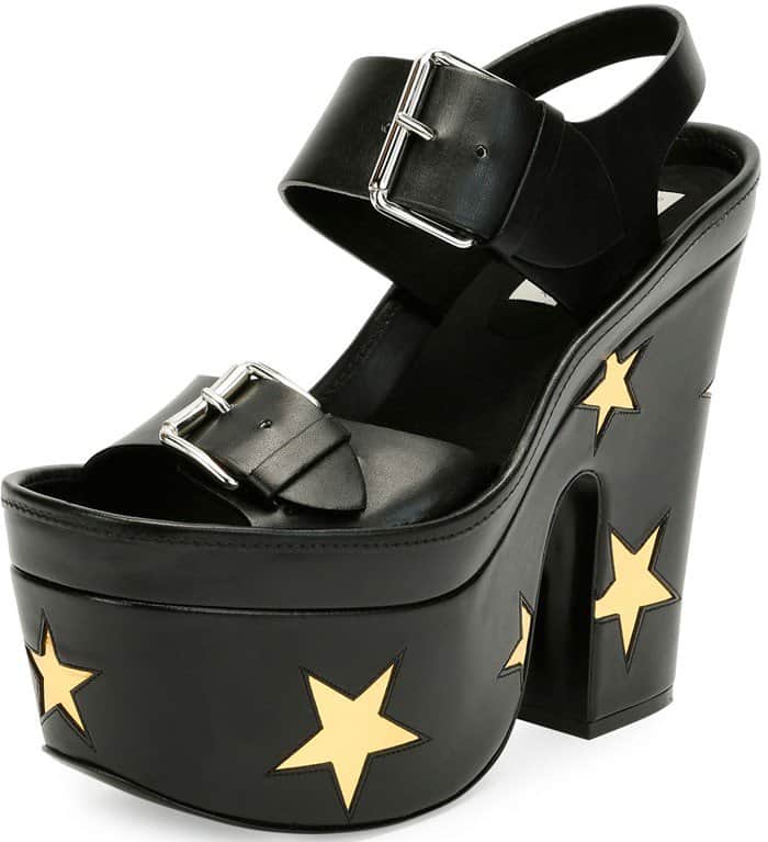 Black faux-leather platform sandals by Stella McCartney feature bold gold star appliqués, chunky heels, and oversized buckle straps for a graphic, statement-making finish