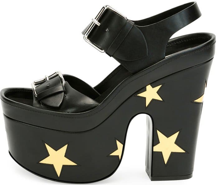Black faux-leather platform sandals by Stella McCartney feature bold gold star appliqués, chunky heels, and oversized buckle straps for a graphic, statement-making finish