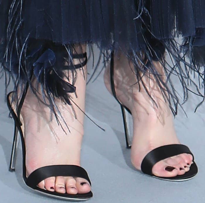 Giuseppe Zanotti black “Georgine” sandals add sleek definition beneath the feathered hem