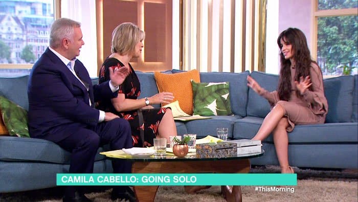 Seated alongside the hosts of “This Morning,” Camila Cabello balanced conversational ease with polished minimalism in a ruffle-sleeved knit dress and sleek nude sandals