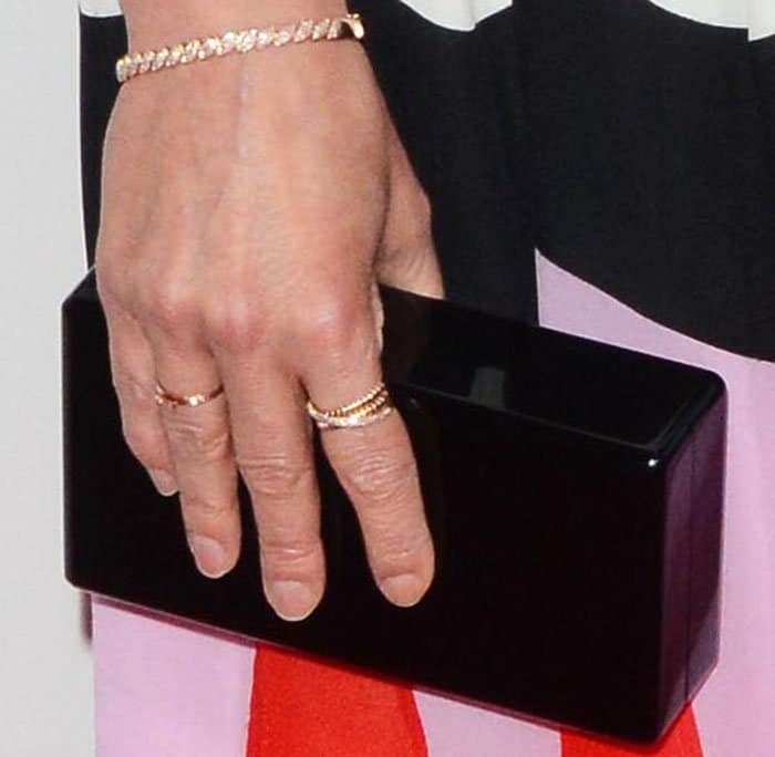 Smulders adds a hint of structure to her playful ensemble with Edie Parker’s glossy black “Jean” box clutch and delicate gold jewelry