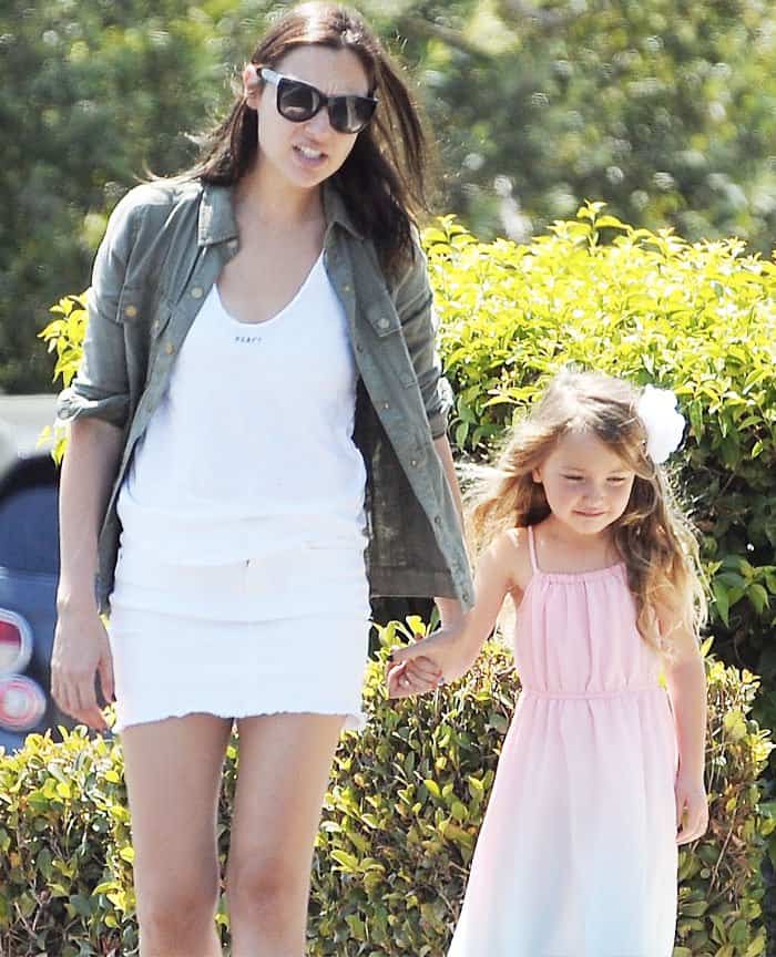Gal Gadot keeps it casual yet stylish with tousled hair and oversized sunglasses, while her daughter Alma looks adorable with loose waves and a white flower hair accessory