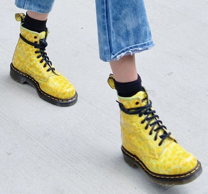 Detailing the bold footwear, Gigi Hadid's yellow Dr. Martens boots showcase a unique croc-patterned leather, proving combat boots can be a vibrant summer statement